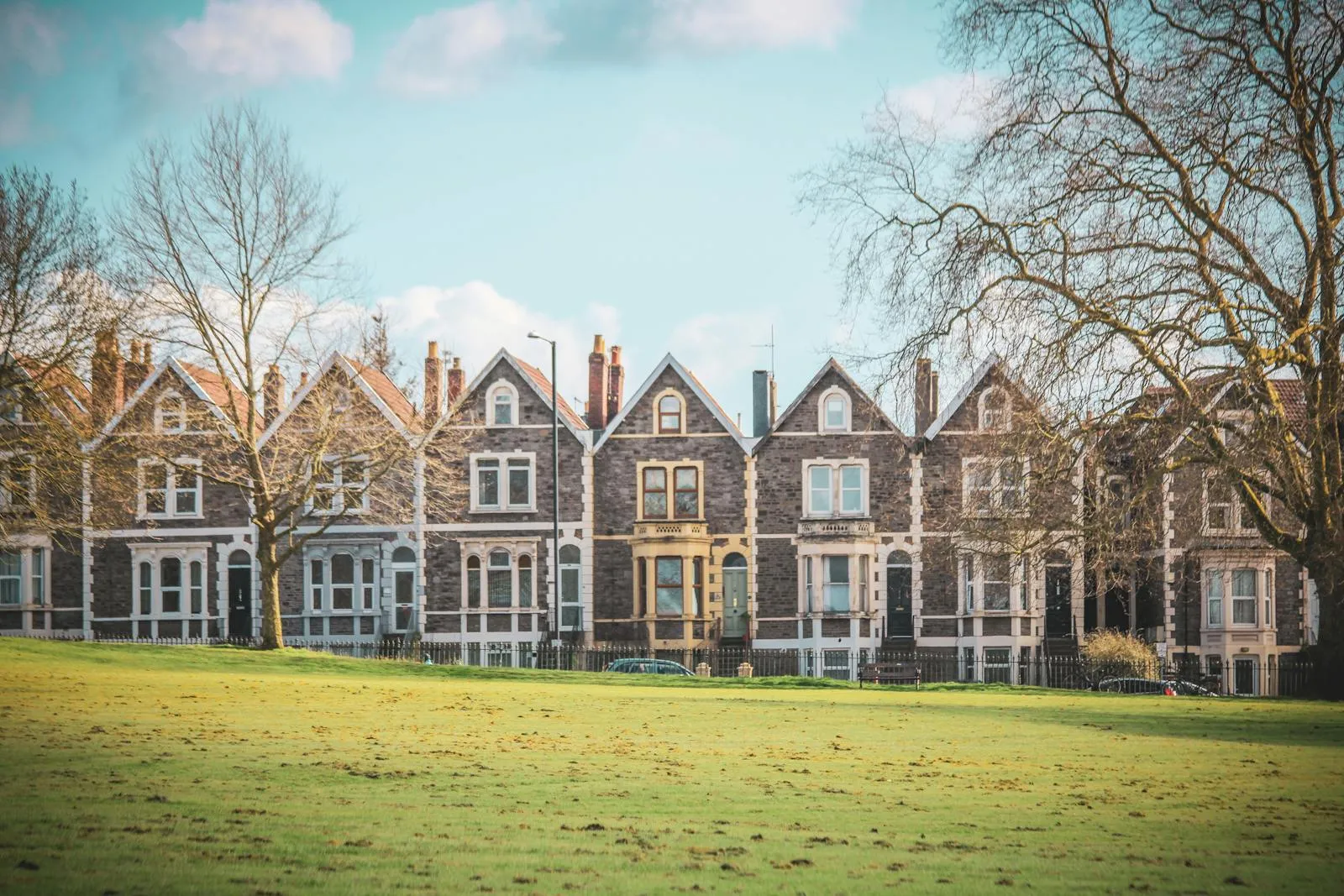 A row of bay-fronted Victorian terraced houses facing a green in Bristol