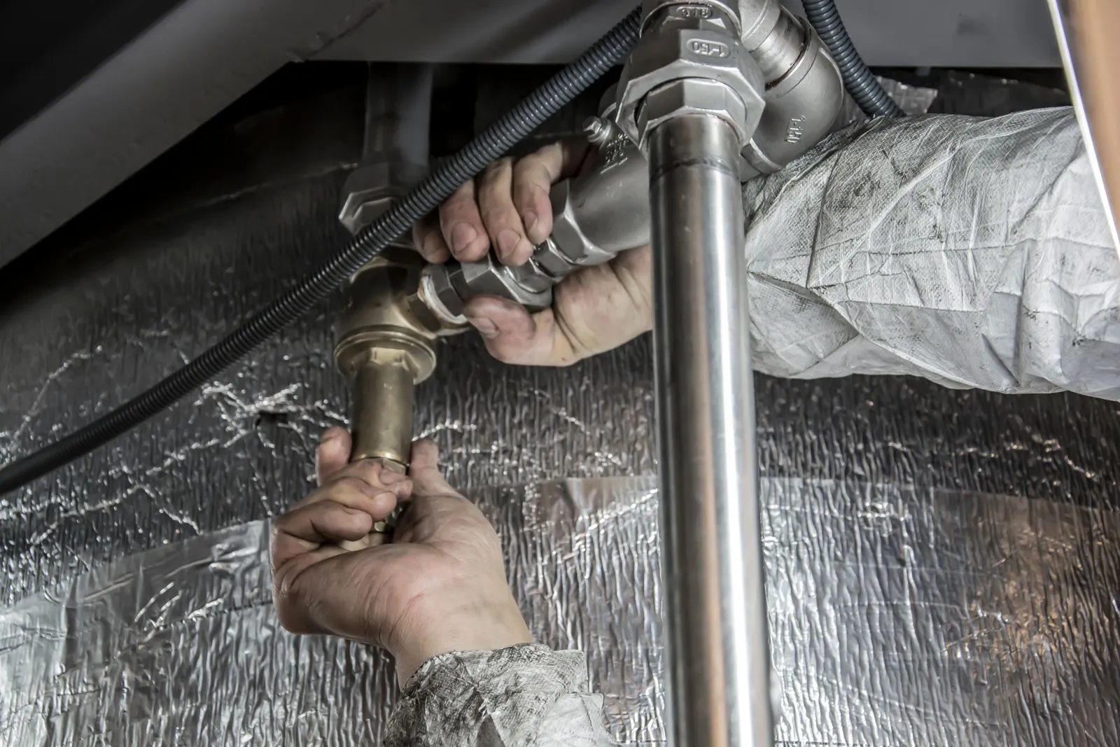 An engineer working on heating pipework — most of an installation week is plumbing inside the house, not work on the outdoor unit.